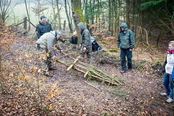 Gruppe baut eine selbstgebaute Konstruktion aus Ästen im Wald