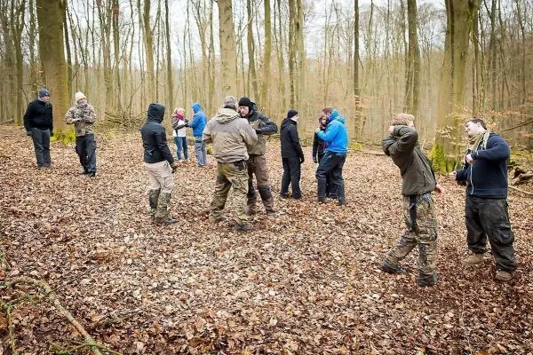Gruppendynamik im Wald mit Teilnehmern in unterschiedlichen Outfits und Aktivitäten