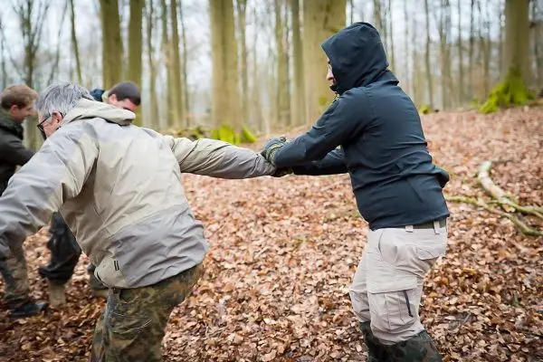 Gruppenteilnehmer ziehen an einem Seil im Laubwald