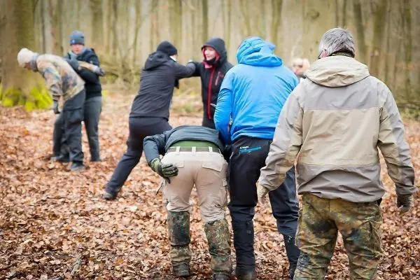 Gruppentraining im Wald mit mehreren Personen in unterschiedlichen Positionen und Aktivitäten