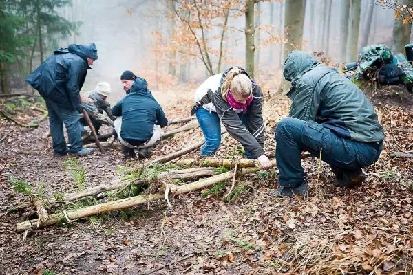 Gruppierung arbeitet an einer selbstgebauten Konstruktion aus Ästen im Wald