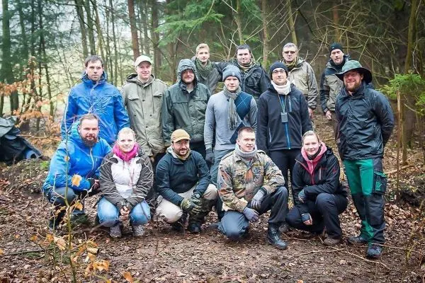 Gruppierung von Personen in Waldumgebung, alle tragen wetterfeste Kleidung