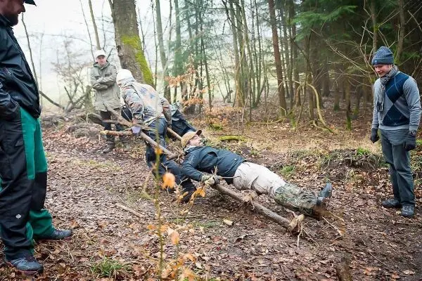 Gruppierung zieht improvisierte Trage mit einer Person durch den Wald