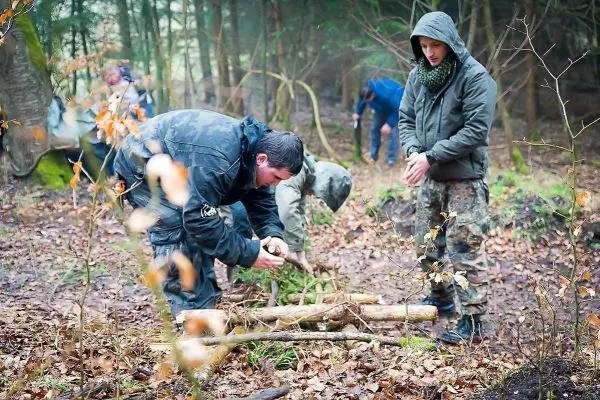 Mann bearbeitet Holzstücke auf dem Boden im Wald