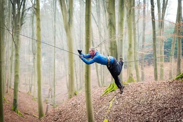 Person balanciert auf selbstgebaute Seilbrücke zwischen Bäumen