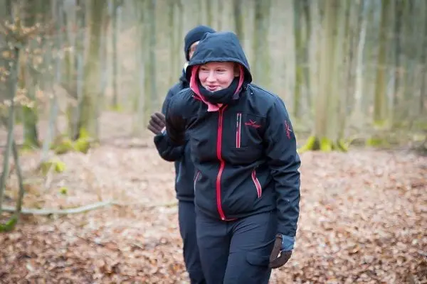 Person geht lächelnd durch den Wald auf Laub