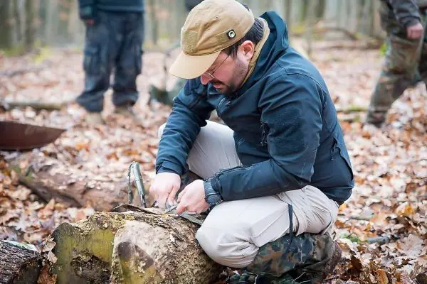 Person schnitzt an einem Holzstück im Wald