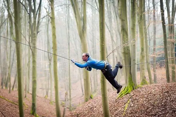 Selbstgebaute Seilquerung wird zwischen Bäumen überquert
