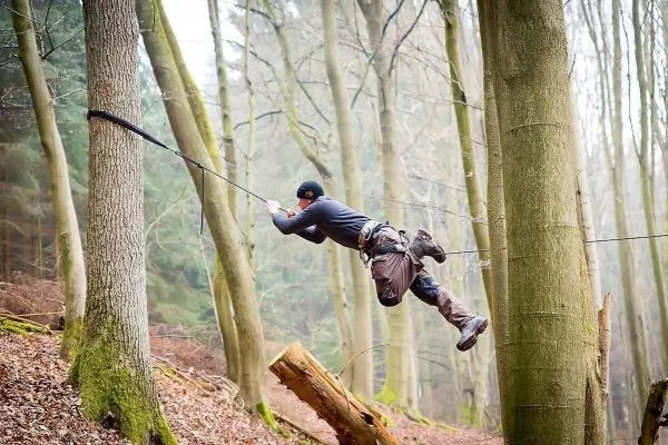 Selbstgebaute Seilquerung zwischen zwei Bäumen wird überquert