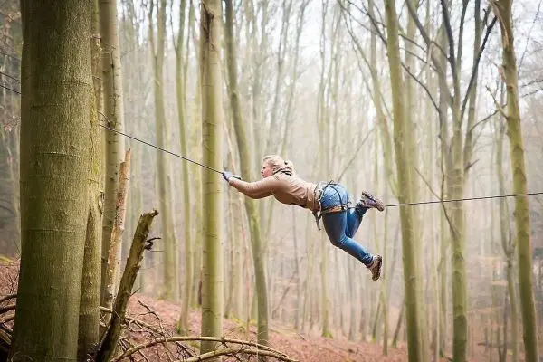 Überquert eine selbstgebaute Seilbrücke zwischen zwei Bäumen
