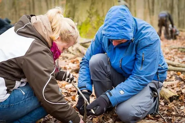 Zwei Personen arbeiten gemeinsam an einer Holzstruktur im Wald