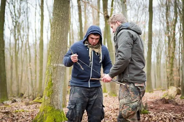 Zwei Personen arbeiten gemeinsam an einer Holzstruktur im Wald