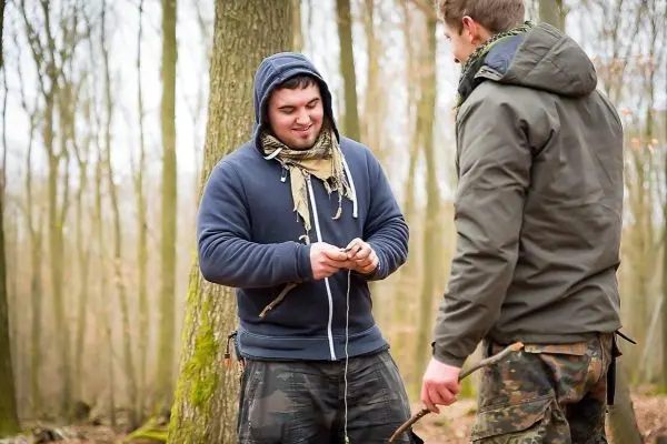 Zwei Personen arbeiten im Wald an einer Schnur oder einem Seil