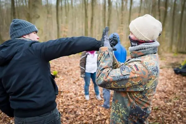 Zwei Personen üben eine Abwehrtechnik im Laubwald