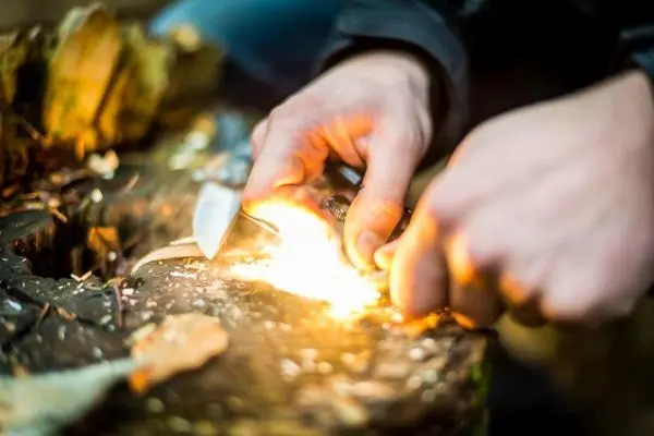 Feuerstahl erzeugt Funken auf Zunder auf einem Baumstamm