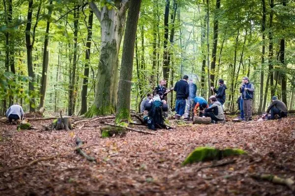 Gruppe von Personen übt im Wald mit Ausrüstung auf dem Boden