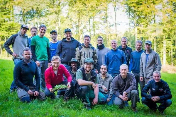 Gruppierung von Männern in Outdoor-Bekleidung auf einer Wiese im Wald