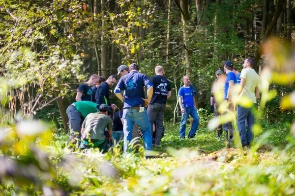 Gruppierung von Personen im Wald, die sich um einen Bodenbereich versammeln