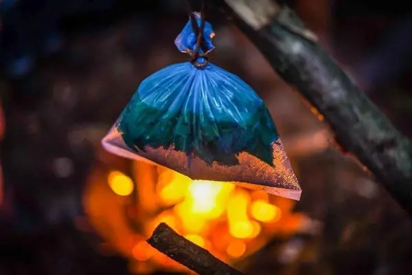 Kunststoffbeutel hängt über einem kleinen Feuer zur Wassererwärmung