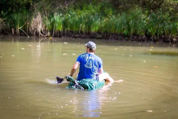 Mann paddelt auf improvisiertem Floß in einem ruhigen Gewässer