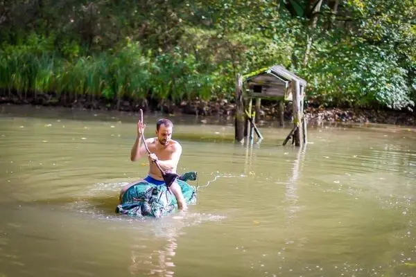 Mann paddelt auf improvisierter Schwimmhilfe durch einen ruhigen Gewässerbereich