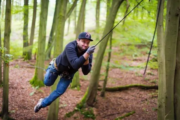 Mann überquert mit Seil eine Waldlichtung