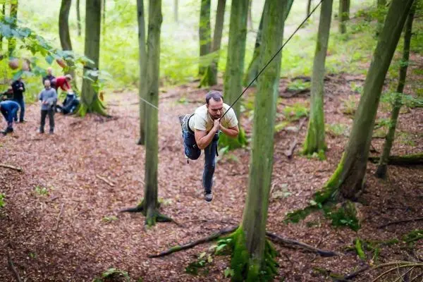 Mann überquert selbstgebaute Seilbrücke zwischen Bäumen im Wald