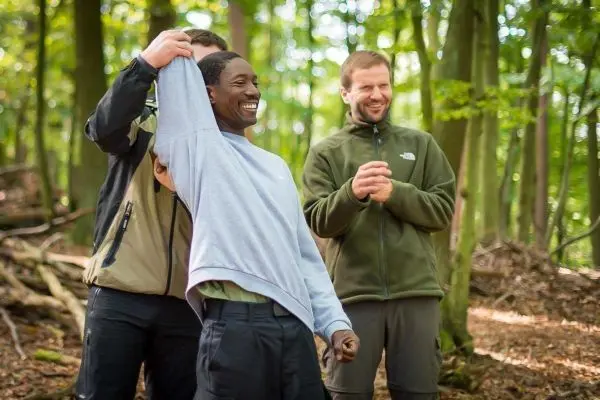 Person hält Kleidung hoch, während andere Personen lachen