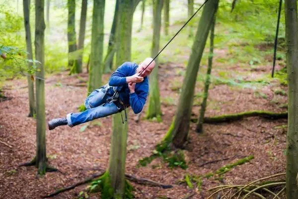 Person schwingt an einem Seil zwischen Bäumen