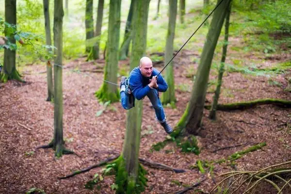 Person schwingt an einem Seil zwischen Bäumen