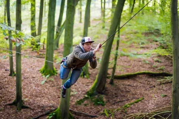 Person schwingt an Seil zwischen Bäumen im Wald