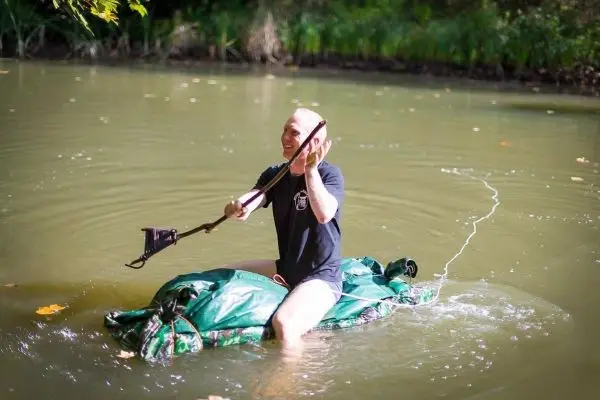 Person sitzt auf einer selbstgebauten Flotte im Wasser