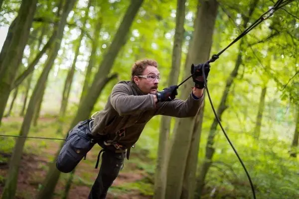 Person zieht sich an einem Seil durch den Wald