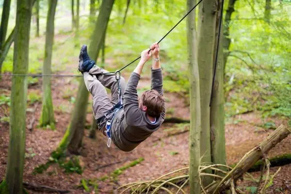Seilquerung an einem gespannten Seil zwischen Bäumen im Wald