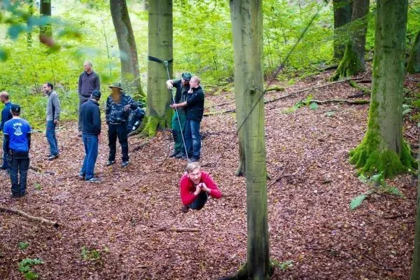 Selbstgebaute Seilquerung zwischen Bäumen mit Teilnehmer in rotem Shirt