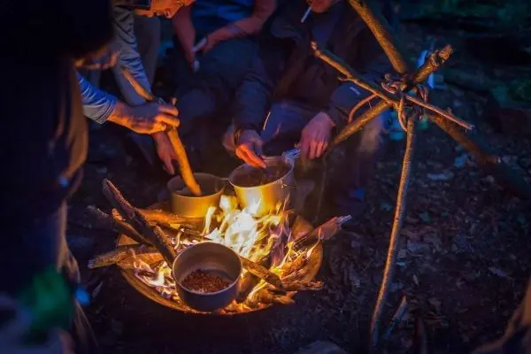 Töpfe über Feuer auf einem improvisierten Dreibein zum Kochen