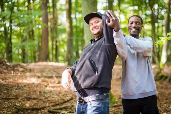Zwei Personen stehen in einem Wald und lachen miteinander