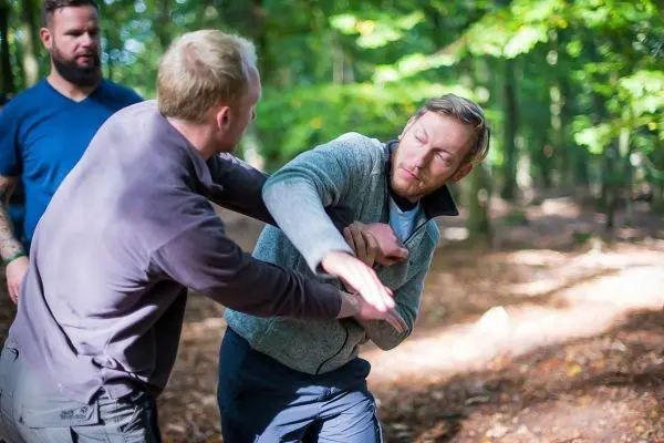 Zwei Personen üben eine Selbstverteidigungstechnik im Wald