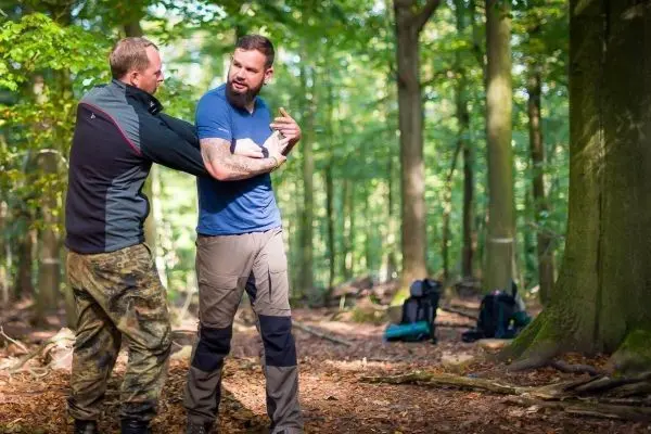 Zwei Personen üben eine Selbstverteidigungstechnik im Wald