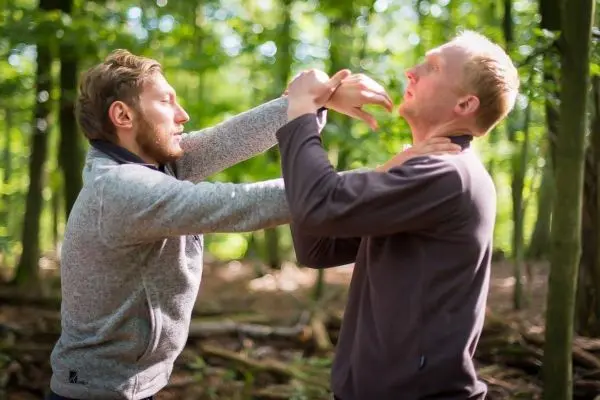 Zwei Personen üben eine Selbstverteidigungstechnik im Wald aus