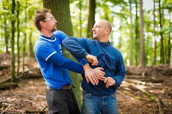 Zwei Personen üben eine Selbstverteidigungstechnik im Wald aus