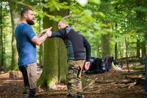 Zwei Personen üben eine Technik zur Selbstverteidigung im Wald