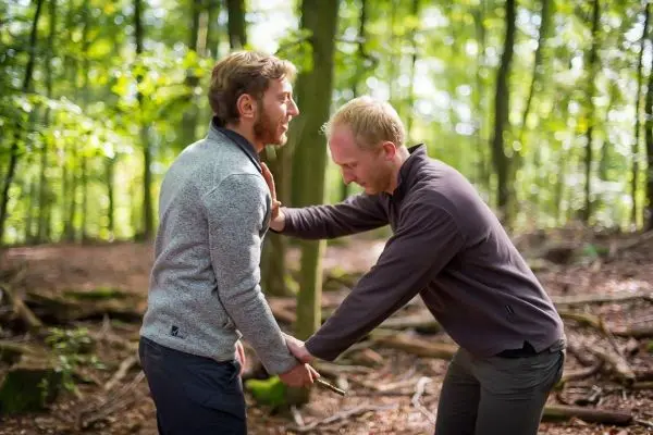 Zwei Personen üben eine Technik zur Selbstverteidigung im Wald aus