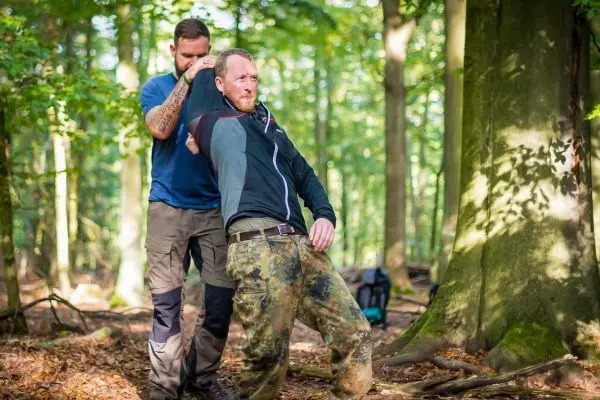 Zwei Personen üben eine Technik zur Unterstützung in einem Waldgebiet