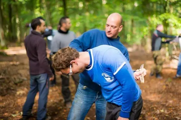 Zwei Personen üben eine Technik zur Unterstützung in einer Waldumgebung