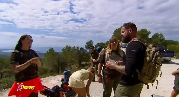 Gruppe mit Rucksäcken steht an einem Weg, diskutiert und bereitet sich vor