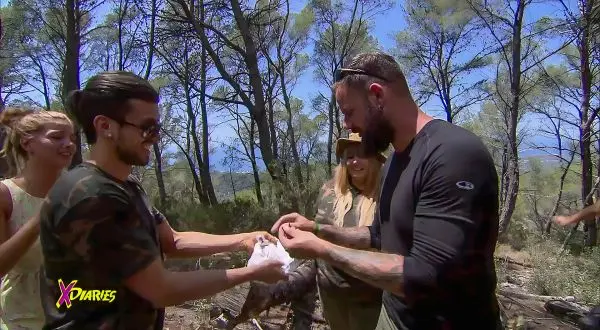 Zwei Personen übergeben sich ein Paket in einem Waldgebiet