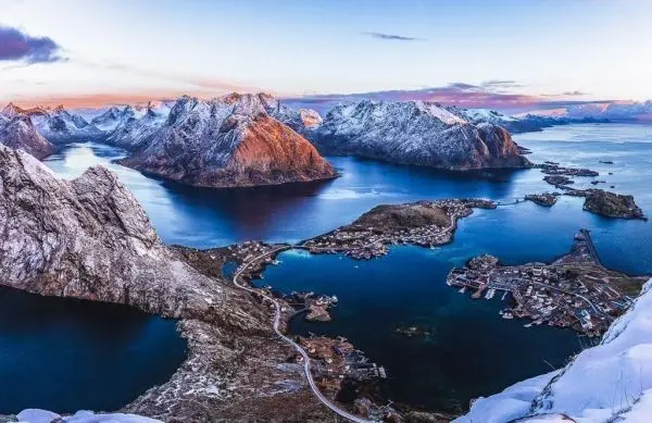 Berglandschaft mit schneebedeckten Gipfeln und fjordartiger Küstenlinie