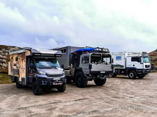Drei geländetaugliche Fahrzeuge stehen auf einem Parkplatz nebeneinander