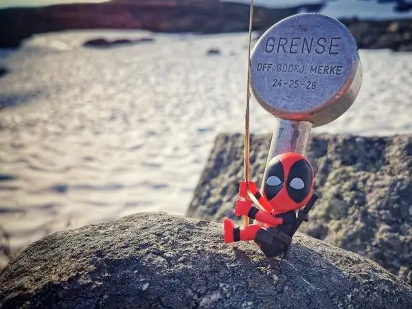 Figur sitzt auf einem Stein und hält eine Schnur an einem Metallpfosten